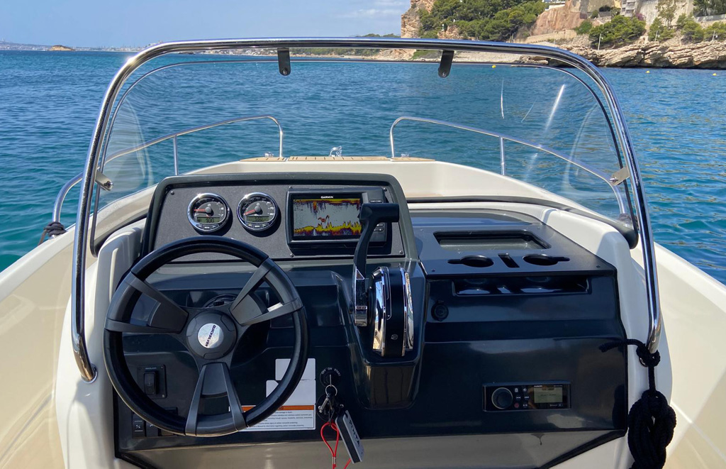 Puesto de mando Quicksilver Activ 605 Open con pantalla Garmin GPS, marcadores, radio Bluetooth y posavasos, con la costa de Altea al fondo