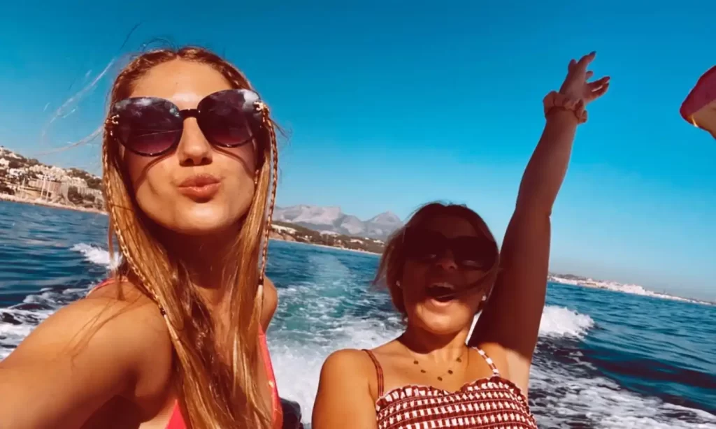 Two friends navigating on a Quicksilver boat in front of the coast of Moraira during a boat trip.