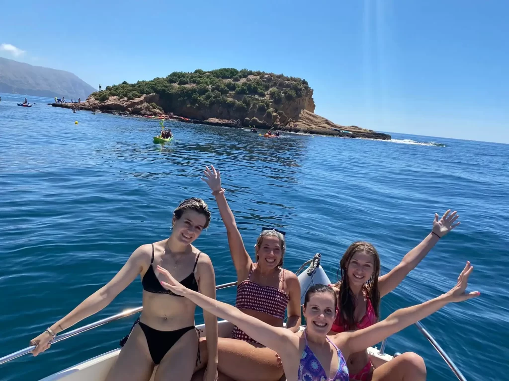 Friends enjoying the bow of a Quicksilver boat in front of Isla de la Olla during a boat rental in Altea on the Costa Blanca.