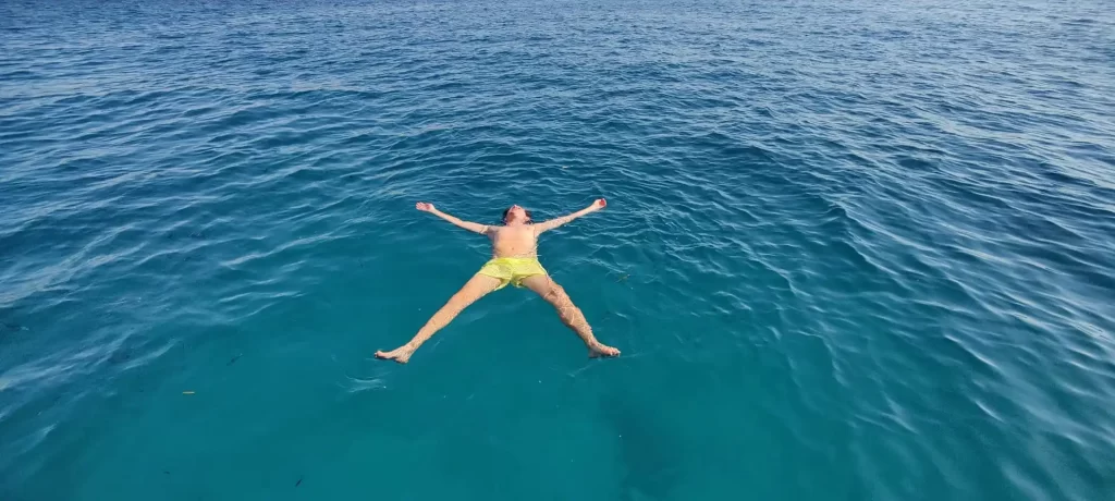 Persona flotando boca arriba en aguas cristalinas de la cala de Mascarat entre Altea y Calpe en la Costa Blanca