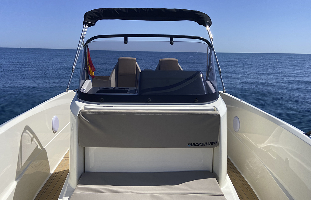 Cubierta de la Quicksilver 605 Open en Altea con asiento de patronera y toldo bimini recogido, barco de alquiler con titulín