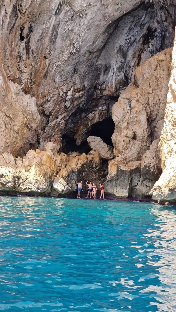 Group of four friends at the entrance of the Mascarat caves swimming in turquoise waters between Altea and Calpe on the Costa Blanca.