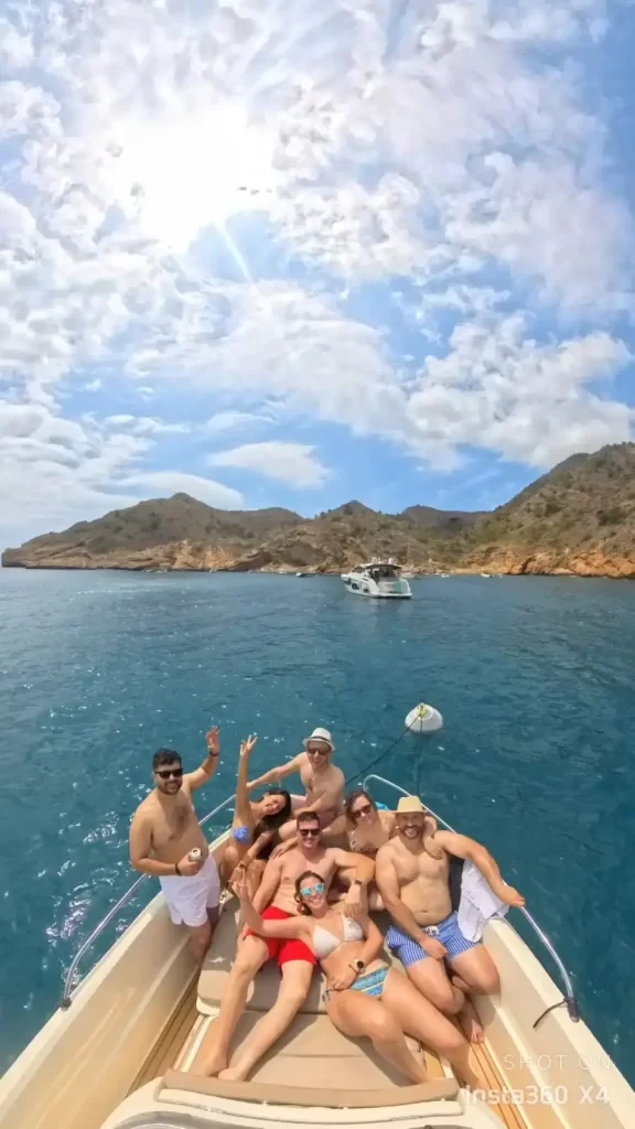 Group of friends taking a selfie lying on the bow of a Quicksilver 605 Open boat navigating along the coast of J&aacute;vea.