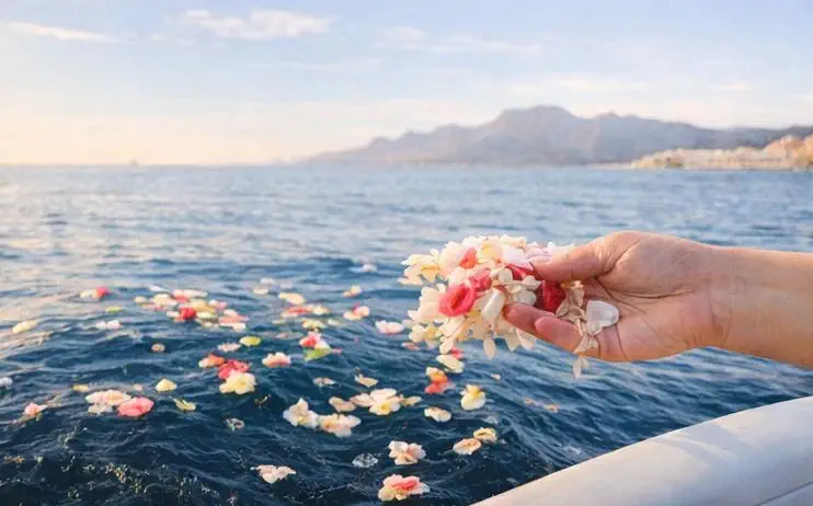 Hand scattering flowers during an ashes ceremony at sea in Altea